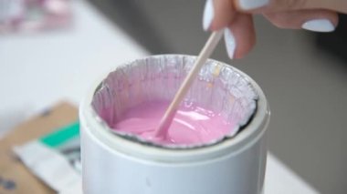 Sıvı pembe tüy dökücü mum ya da yakın plan tahta çubuğa şeker yapıştırıcı. Tüy dökme işleminden önce, usta ısıtma balmumunu ahşap bir spatulayla karıştırır, güzellik salonu..