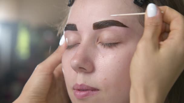 アイブロー ティント ブラシで眉毛染料を塗ったマスターのクローズアップ 化粧品の処置 永久的な眉の構造 美容室で眉毛の修正とモデリング 完璧な眉毛 — ストック動画