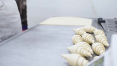 Hamuru kruvasan şekline sokuyorum. Esnaf tatlısı. Modern fırın. Baker kruvasanları şekillendirir. Fransız kruvasanı pişiriyorum. Puf böreği, kruvasan, puf. Gıda endüstrisi, şekerlemeler.