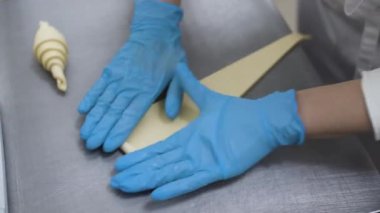 Hamuru kruvasan şekline sokuyorum. Esnaf tatlısı. Modern fırın. Baker kruvasanları şekillendirir. Fransız kruvasanı pişiriyorum. Puf böreği, kruvasan, puf. Gıda endüstrisi, şekerlemeler.