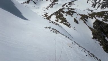 Serbest stil bir kayakçı, manzaralı dağlarda kayak yaparken taze karı kesiyor. Aktif bir erkek turiste doğru uçuyoruz. Nefes kesici bir arazide kayak yapıyor.