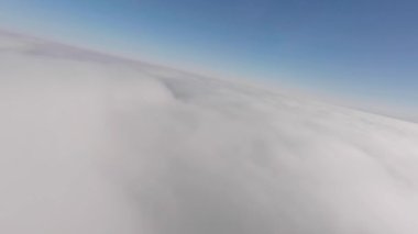 Güneşli bir günde sislerin üzerinde alçaktan uçan hava manzarası. Drone kanadı bulut sörfü yapıyor. Rüyadaki gibi. Kuşların bakış açısı