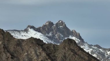 Avrupa Alpleri 'nin kayalık tepeleri arasında kışın karla kaplı hava manzaralı bir uçuş. Doğal video arkaplanı.