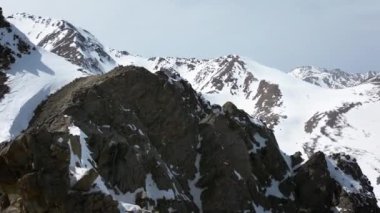 Avrupa Alpleri 'nin kayalık tepeleri arasında kışın karla kaplı hava manzaralı bir uçuş. Doğal video arkaplanı.