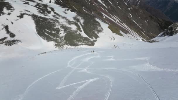 スカートのスキーヤーのグループは 山の雪の斜面に立っています スキーツーリング フリーライド エアリアルビュー — ストック動画