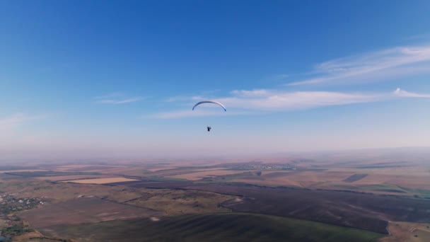 空中的景色 地平线上的稳定镜头 一只雄性的滑翔机被田野和山丘环绕着 晴天蓝白滑翔翼 — 图库视频影像