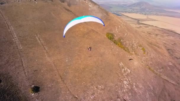 从一个运动Fpv无人机的空中俯瞰 一名滑翔伞运动员在一座小山的斜坡附近飞行 从Fpv无人机免费飞越农村地区的秋季视频 — 图库视频影像
