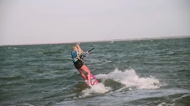 テレフォトレンズのスローモーション 若い女性アスリートは大きな波で風の強い天気のキットボードに乗ります — ストック動画