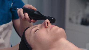 Lenfatik drenaj masajı donanım işlemidir. Bir kozmetolog-terapist bir mankene güzellik salonunda canlandırıcı bir yüz masajı yapar. Yakın plan..