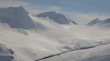 Kar ve bulutlarla çerçevelenmiş yüksek kayalık dağlar, mavi gökyüzü, hiç kimse. Yüksel..