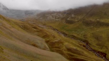 Kuzey Kafkasya vadisinde havadan gelen zaman kaybı. Dağ zirveleri arasında nehrin üzerinde uçan bir dron, bulutların üzerinde hareket ediyor.