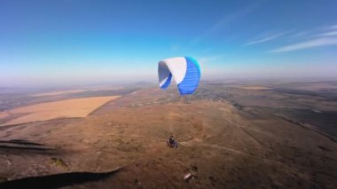 Bir FPV kuadkopterinde çekildi. Güneşli bir günde alçak bir dağın yanında yamaç paraşütü yapan bir sporcu uçar. Hava görüntüsü Adrenalin Konsepti, İHA Atışı.