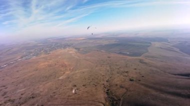 Bir FPV kuadkopterinde çekildi. Güneşli bir günde alçak bir dağın yanında yamaç paraşütü yapan bir sporcu uçar. Hava görüntüsü Adrenalin Konsepti, İHA Atışı.