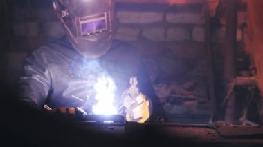 Metal kaynakçı evde çelik kaynak yapmak için yay kaynakçısıyla çalışır, güvenlik ekipmanları kullanır. Evde metal yapıların onarımı ve üretimi.