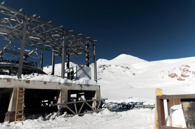 Kışın yüksek dağlarda inşaat halindeki bir teleferik istasyonu. Karla kaplı kalın bir teleferik kablosuna odaklan..