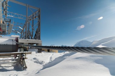 Dağlarda yapım aşamasında olan bir teleferik istasyonu. Karlı dağ manzarası ve teleferik için metal bir yapı..
