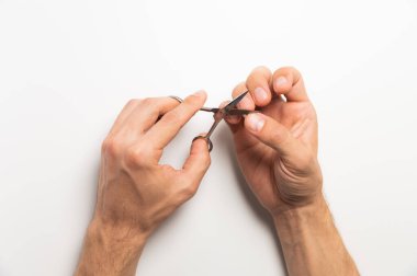 Erkek eller manikür yapıyor. Makas, beyaz bir arkaplanda el tırnağı kesiyor..