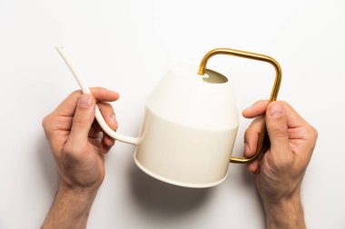 Bahçe işleri konsepti. Bir adam elinde sarı bir sulama tenekesi tutar beyaz bir arka plan, yakın çekim üst görünüm.