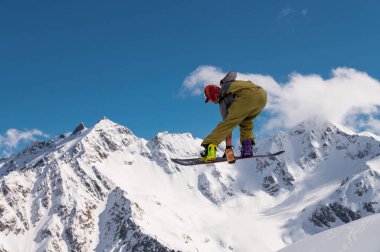 Karlı yamaçta uçan snowboardcu. Kış sporları, snowboard sporları.
