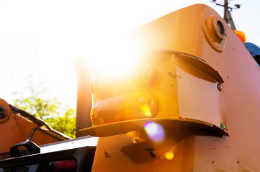 Arkasından güneş ışığı alan bir kazıcının yakın görüntüsü. Küçük bir kazıcının arka farları.