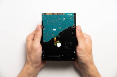 Beyaz arka planda bir el sabit diski tutuyor. Erkek elleri aygıtı gösteriyor.