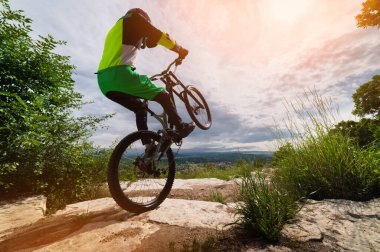 Bir bisikletçi arka tekerine biner. Bisiklet, dağ bisikleti sürerken denge sağlar. Tekerlekli sandalyede dublörlük yapmak riskliydi..