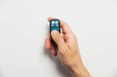 Kapı ya da garaj için uzaktan kumanda ya da beyaz arka planda erkek eli. Modern teknolojiler ve ev koruması.