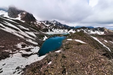 Güzel bir yaz gününde göl manzarası ve karla kaplı dağların manzarası. Zirvenin panoramik manzarası ve dokunulmamış doğanın güzelliği.