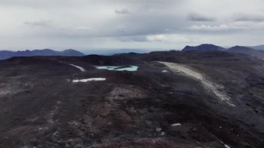 Volkanik kayalar ve cansız bir manzarayla çevrili buzul bir turkuaz göl. İzlanda hava görüntüsü.