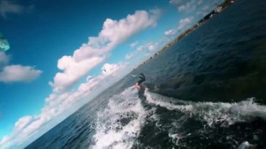 Güneşli bir akşamda sörf tahtası. İnsansız hava aracıyla bir FPV sporcusunu takip etme görüntüsü. Su üzerinde alçaktan yakın uçuş. Rüzgarlı deniz sporları. Yavaş çekim.