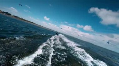 Kiteboardcu uçurtma sürüyor ve hileli bir atlayış yapıyor. Gölde sörf tahtası, atleti takip eden İHA görüntüleri..