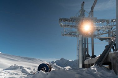 Güneşli bir günde yüksek dağlarda inşaat halindeki bir halat sistemi. Bir dağ manzarasında depreme dayanıklı metal bir yapı..