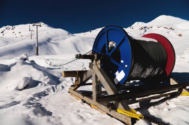 Güç kablosu bobinlerde. Kalın elektrik teli. Açık hava kullanımı için tel makara. Kar altında bir kayak merkezinde elektrik ürünleri..