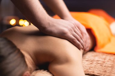 Masör yakın planda masaj yapıyor. Mum ışığı ayarı, spa salonu, dinlenme günü..