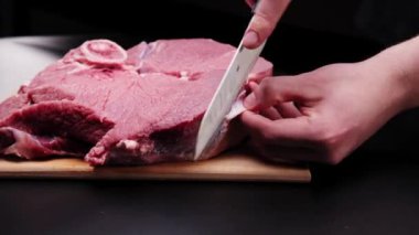 Eldivenli kasap, kırmızı et parçalarını kesiyor. Kasap dükkanında ahşap tahta keserken büyük bir parça et kesilen bıçağın yakın çekimi. Evdeki adam aile yemeği hazırlıyor..