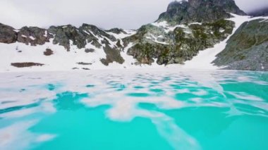 FPV insansız hava aracı çarpıcı mavi alp gölü boyunca hızla ilerliyor. Su yüzeyinde yansıyan İtalyan Dolomite dağlarını yansıtıyor. Hava görünümü