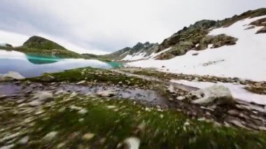 FPV insansız hava aracı çarpıcı mavi alp gölü boyunca hızla ilerliyor. Su yüzeyinde yansıyan İtalyan Dolomite dağlarını yansıtıyor. Hava görünümü