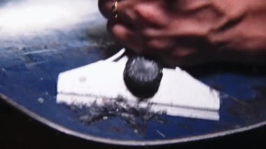 Bir kadın eli, kaygan bir snowboard yüzeyinden fazla balmumu kazıyor. Kayak malzemeleri bakım atölyesi. Yakın plan. Sığ alan derinliği