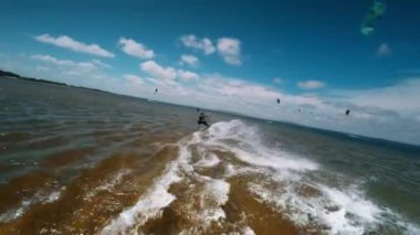 Profesyonel mutant, güzel su sıçratmaların ve harika manzaraların arka planına karşı zor bir numara sergiliyor. Dişi uçurtma sörfçüsü ağır çekimde bir numara yapıyor..