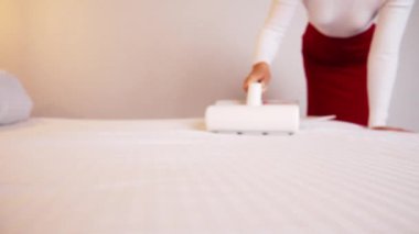 Elinde elektrikli süpürge olan bir kadın döşemeleri temizliyor. Toz ve akarlardan döşenmiş mobilyaları işliyor, temizliyor. Uyuduktan sonra yatağı temizlemek, ultraviyole ile elektrikli süpürge..