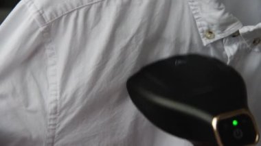 Genç bir kadın, karanlık bir odada beyaz bir adamın gömleğini buharlı ütülüyor. Demir yerine buharlı gemi kullanmak..