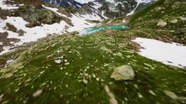 Bir FPV insansız hava aracının havadan görüntüsü bir dağ gölüne akan bir nehrin çağlayanı üzerinde alçaktan uçuyor. Dağların yükseklerindeki dağ rezervleri. Yüksek hızda çok alçaktan uçuyor..