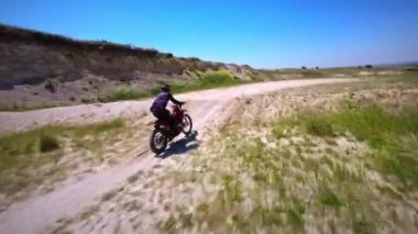 Motosikletli, Tozlu Tepe yolunda motosiklet sürüyor. Profesyonel sporcu, yüksek dağlarda modern motosiklet manevrası yapıyor. Vahşi doğayı fethediyor, yarışçı için fpv üzerinde uçuyor..
