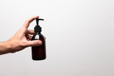 Beyaz bir arka planda elinde pompayla büyük bir plastik şişe tutan genç bir kadın. Vücudun temiz ve yumuşak cildiyle ilgilenmek. Günlük kozmetik ürünü.