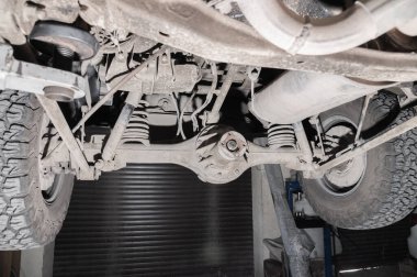 Arabanın altından yakın çekim görüntüsü. Bir off-road aracının kirli süspansiyonu. Aktarım bileşenleri.