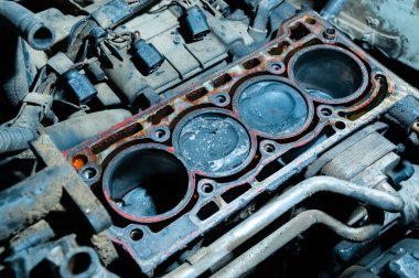 Parçalanmış içten yanmalı bir motor. Motor bloğunda karbon birikintileri ve kırık metal parçaları olan kirli pistonlar var. Araba bakımı eksikliği ve zamansız motor servisi kavramı