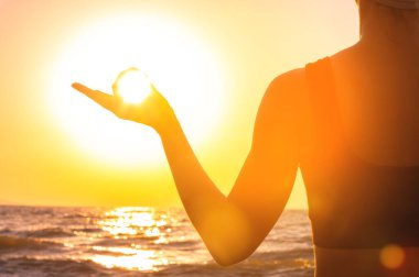 Gün batımında Gyan Mudra 'da meditasyon yapan adamı yakından çek. Kadın eli güneş ve denize karşı, parmakları meditasyon sırasında Mudra 'yı gösteriyor, doğada sakinlik ve sükunet..