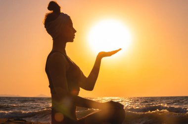 Gün batımında Gyan Mudra 'da meditasyon yapan adamı yakından çek. Kadın eli güneş ve denize karşı, parmakları meditasyon sırasında Mudra 'yı gösteriyor, doğada sakinlik ve sükunet..