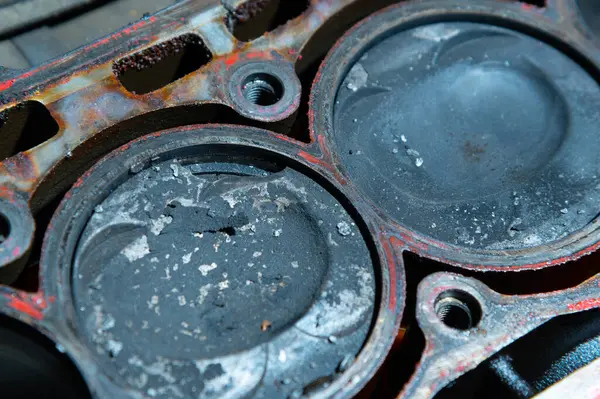 Parçalanmış içten yanmalı bir motor. Motor bloğunda karbon birikintileri ve kırık metal parçaları olan kirli pistonlar var. Araba bakımı eksikliği ve zamansız motor servisi kavramı