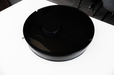 Siyah akıllı elektrikli süpürge beyaz masada. Akıllı ev akıllı temizlik